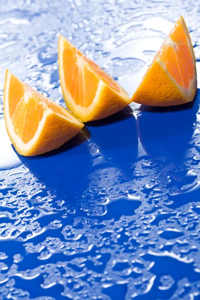 Fette di arancia su superficie blu — Foto Stock