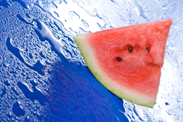 Watermelon slice on blue surface — Stock Photo, Image