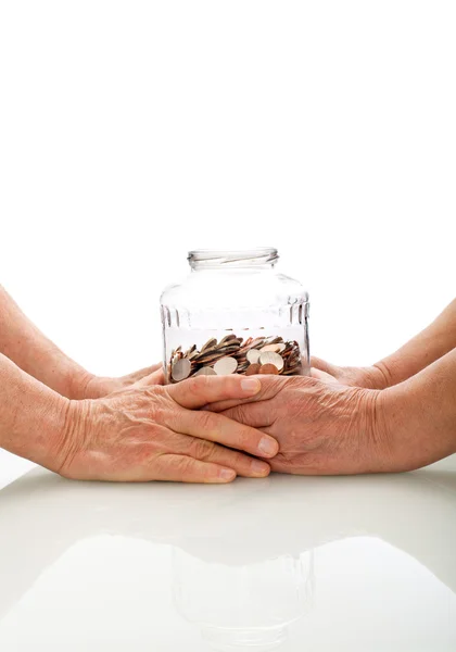 Старшие руки держат банку с монетами — стоковое фото