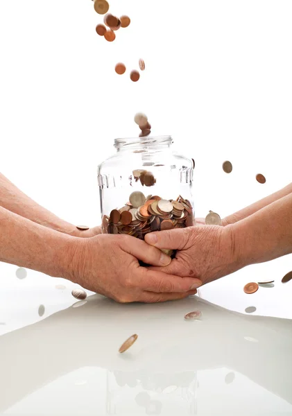 Mãos idosas segurando frasco pegando moedas caindo — Fotografia de Stock