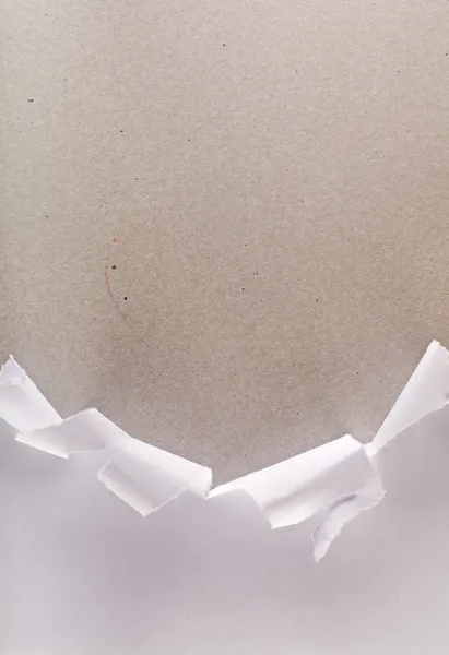 Порванная оберточная бумага, открывающая картонную коробку — стоковое фото