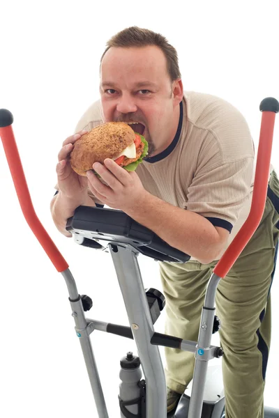 Mężczyzna jedzenie hamburgerów ogromny na urządzenie trener — Zdjęcie stockowe