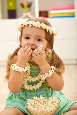 Happy little girl eating popcorn clipart