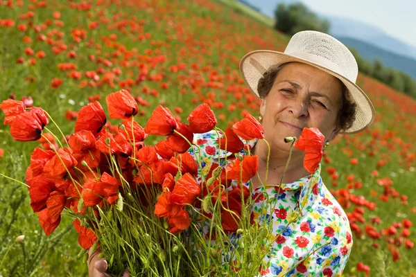 Starszy kobieta na pole Maków z bukiet kwiatów — Zdjęcie stockowe