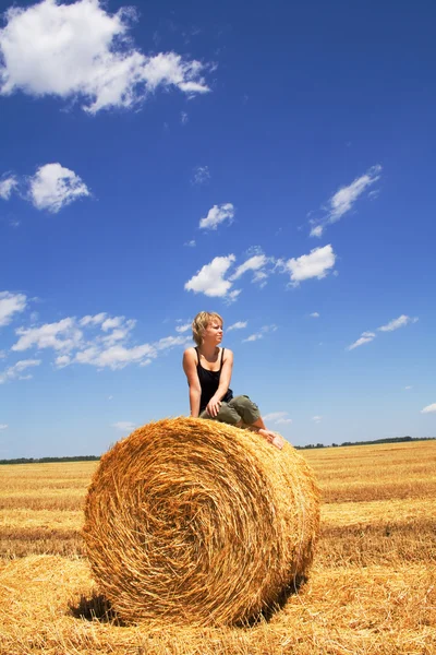 Женщина сидит на тюке сена — стоковое фото