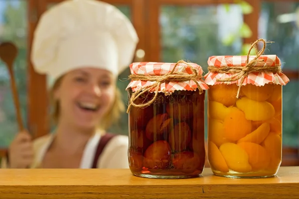Happy woman chef with homemade canned fruit — Stock Photo, Image