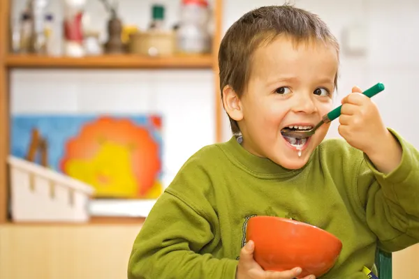 Happy boy eating breakfast - cereals and milk — Stock Photo, Image