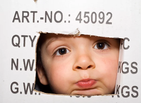 Bambino annoiato che sbircia fuori da una scatola di cartone — Foto Stock