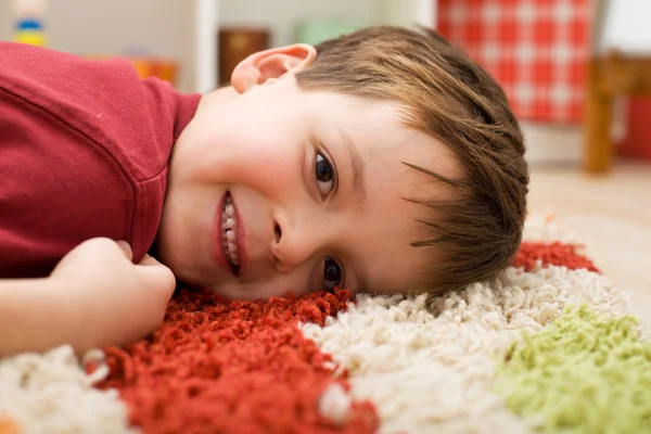 Menino feliz deitado em um tapete — Fotografia de Stock