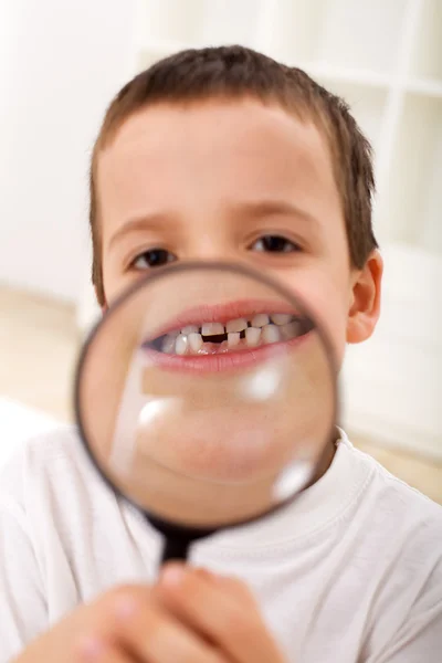 Ilk kayıp diş - büyüteç ile çocuk — Stok fotoğraf