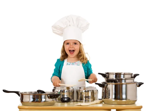 Щаслива маленька дівчинка з капелюхом шеф-кухаря робить шум з кулінарним по — стокове фото