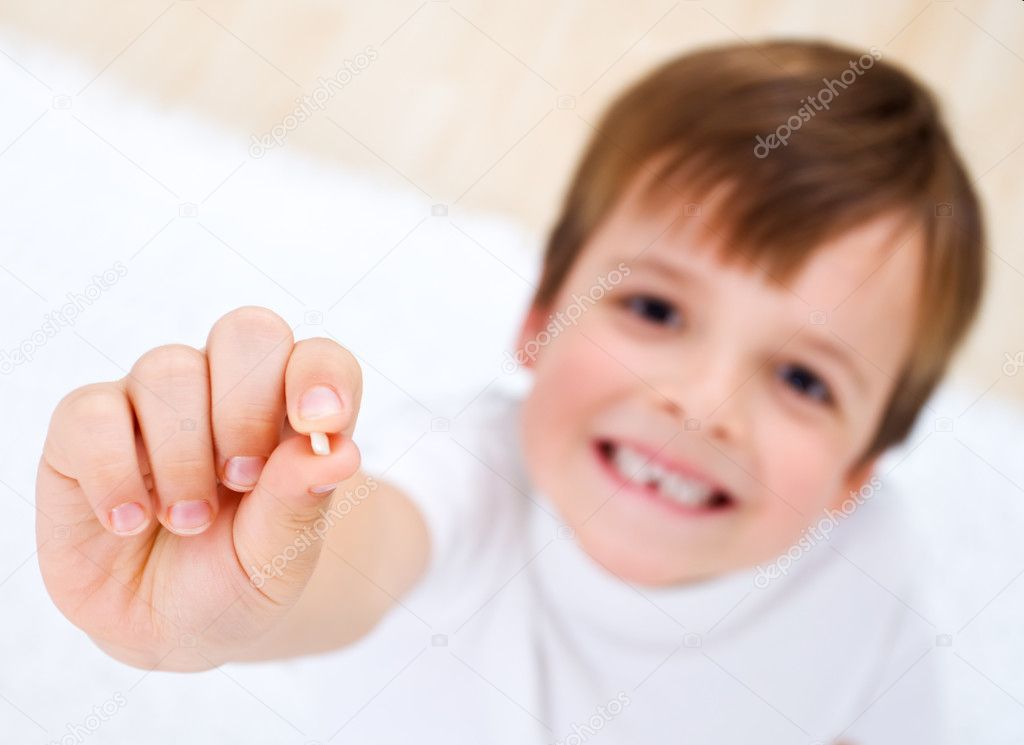 Little boy showing his milk-tooth in his hand