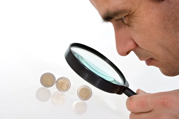 Чоловік уважно дивиться на монети євро — стокове фото