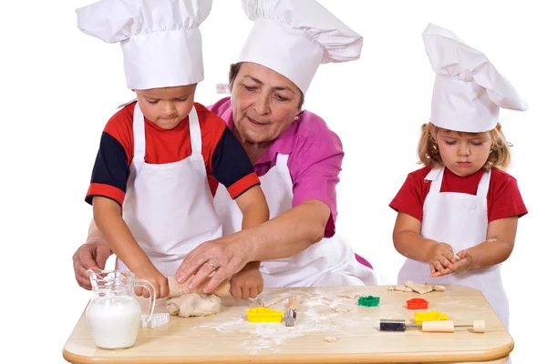 Бабушка учит детей печь печенье — стоковое фото