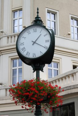 Old style street clock with flowers clipart