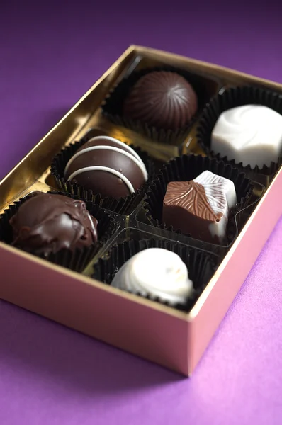 Chocolates sortidos em uma caixa colorida dourada Imagem De Stock