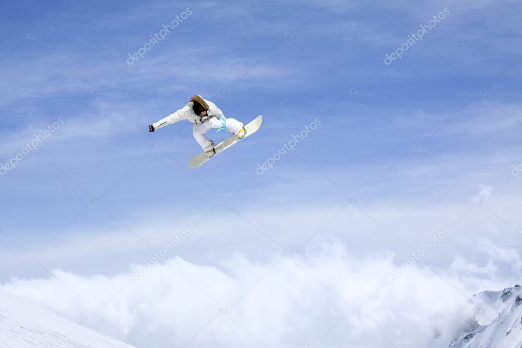 Snowboarder jumping through air with sky in background