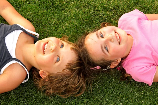 Две улыбающиеся девушки лежат на траве — стоковое фото