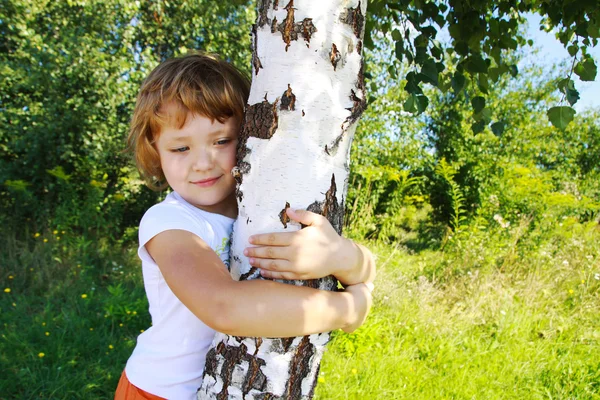 Sorge für die Natur - kleines Mädchen umarmt einen Baum Stockbild