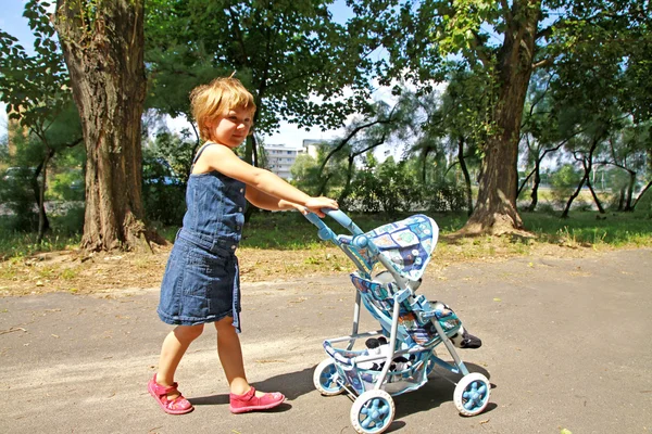 Una bambina con carrozzina giocattolo — Foto Stock