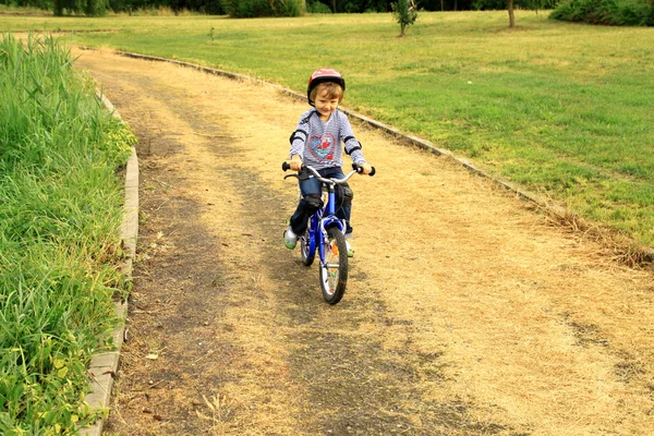 Bambina va in bicicletta nel parco — Foto Stock