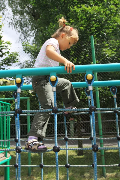 A girl walking on the ladder at the playground — Stock Photo, Image