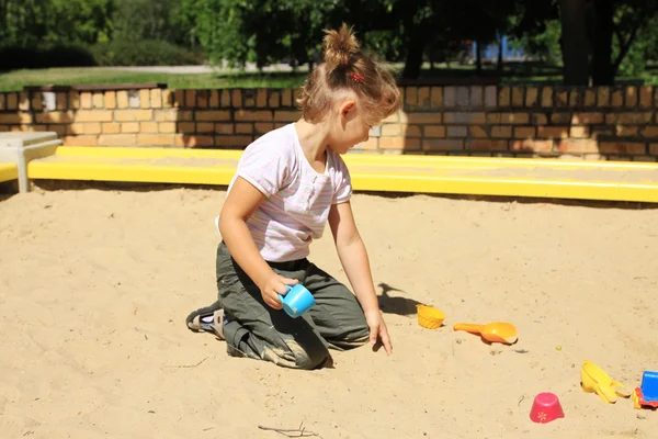 Молодая девушка наслаждается в песочнице — стоковое фото