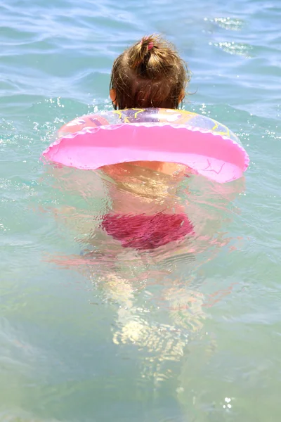 Dívka plave v moři v růžové kolečko — Stock fotografie