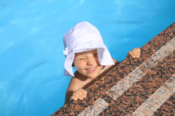这顶帽子的年轻女孩在游泳池中游泳 图库图片
