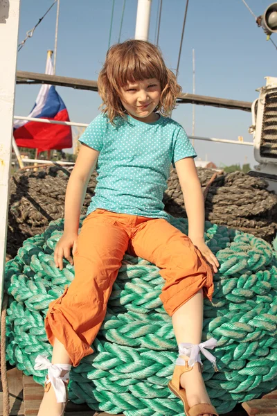 La chica se sienta en una gruesa bobina de cuerdas — Foto de Stock