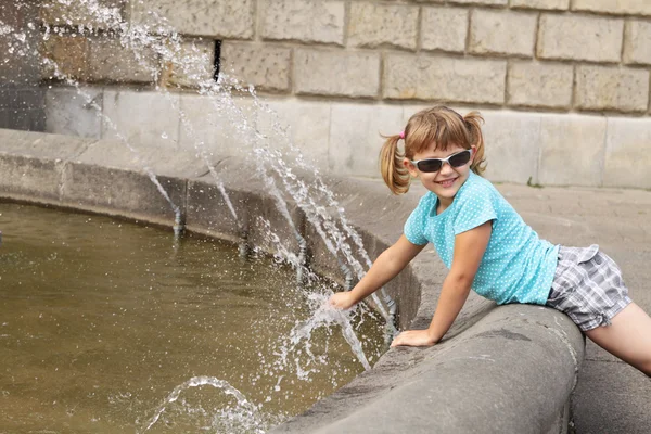 Fille jouer avec l'eau d'une fontaine — Photo
