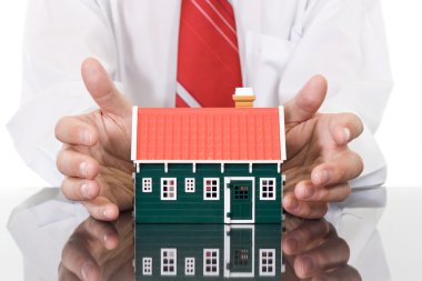 Businessman hands protecting a house clipart