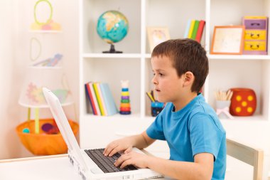 Boy playing or working on laptop computer clipart