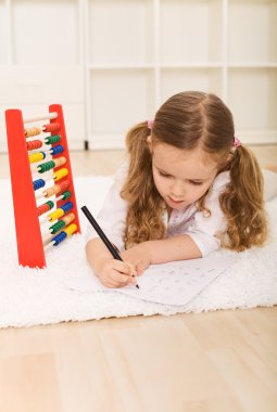 Little girl doing simple math exercises clipart