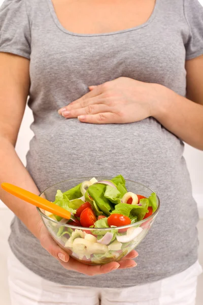 Беременная женщина с миской салата — стоковое фото