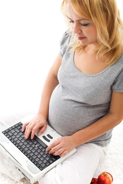 Mooie zwangere vrouw zittend op de vloer met laptop — Stockfoto