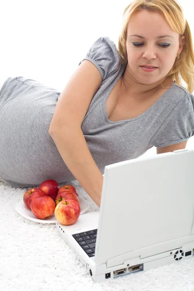 Gravid kvinna med laptop och äpplen — Stockfoto
