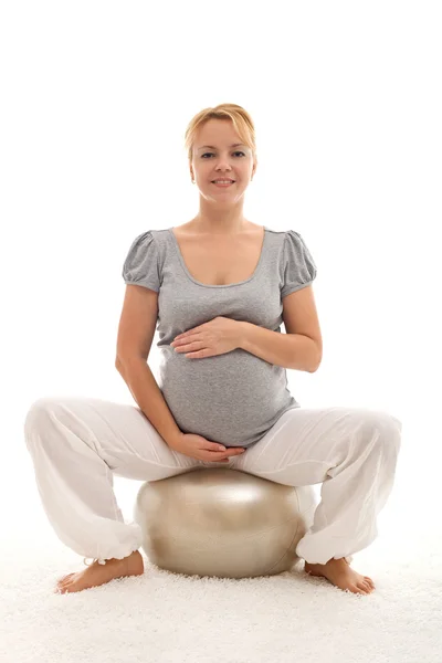 Gravid kvinna som sitter på stora övning boll — Stockfoto