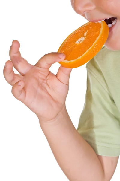 Närbild av kid äta en orange skiva — Stockfoto