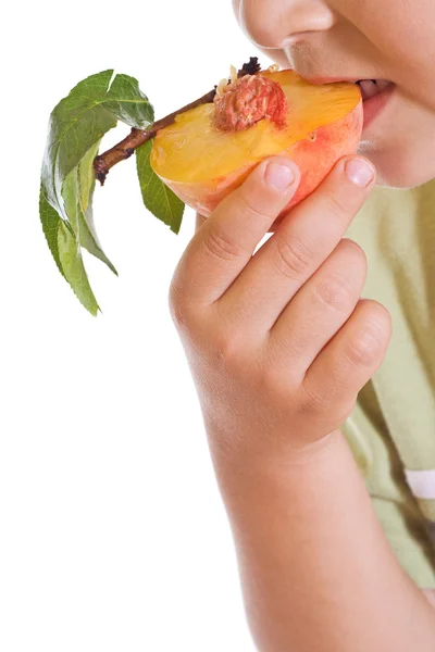 Närbild av kid äta en halv persika — Stockfoto