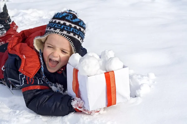 Счастливый мальчик в снегу с коробкой снежков — стоковое фото
