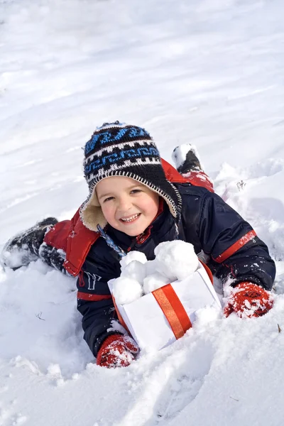 Happy boy in the snow with snowballs in a box — Stock Photo, Image