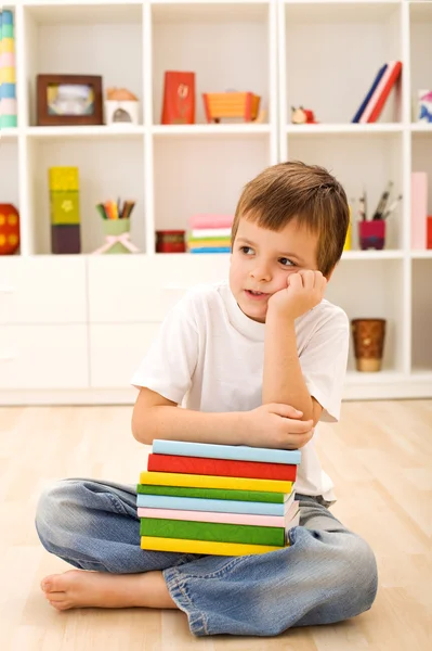 Chłopiec z dużą ilością książek myślenia — Zdjęcie stockowe