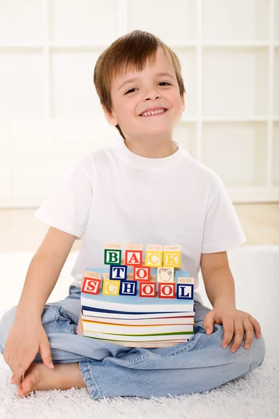 Glückliches Kind mit Schulbüchern auf dem Boden sitzend — Stockfoto
