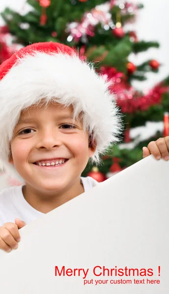 Happy boy with christmas hat and blank sign — Stock Photo, Image