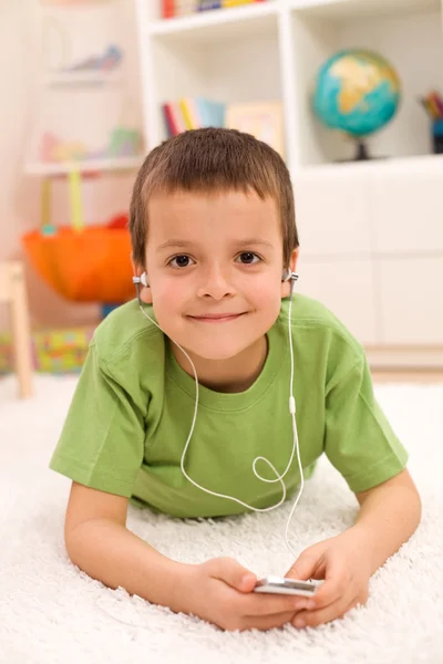Happy boy listening to music laying on the floor — Stock Photo, Image