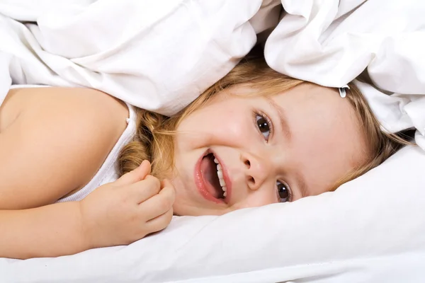 Menina deitada na cama sob a colcha — Fotografia de Stock