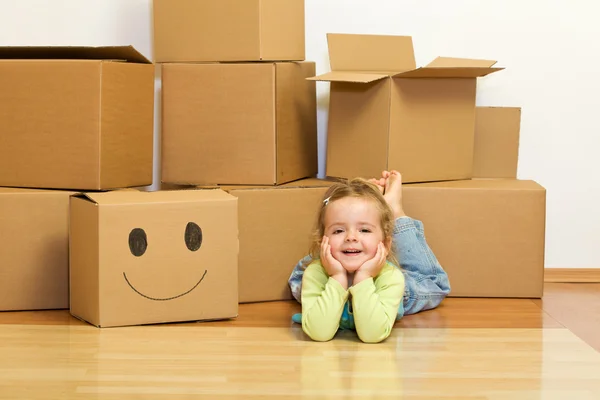 Little girl laying on the floor with lots of cardboard boxes — Stock Photo, Image