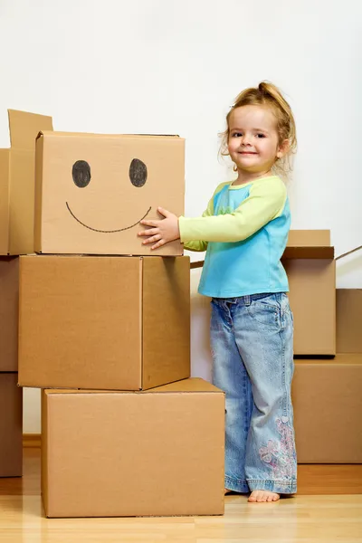 Маленька дівчинка з великою кількістю картонних коробок посміхається — стокове фото