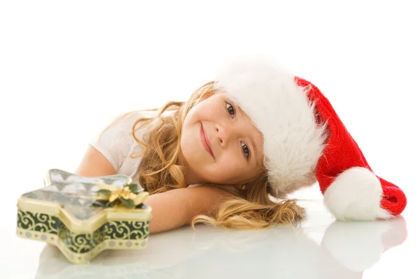Happy little girl with santa hat and christmas present — Stock Photo, Image
